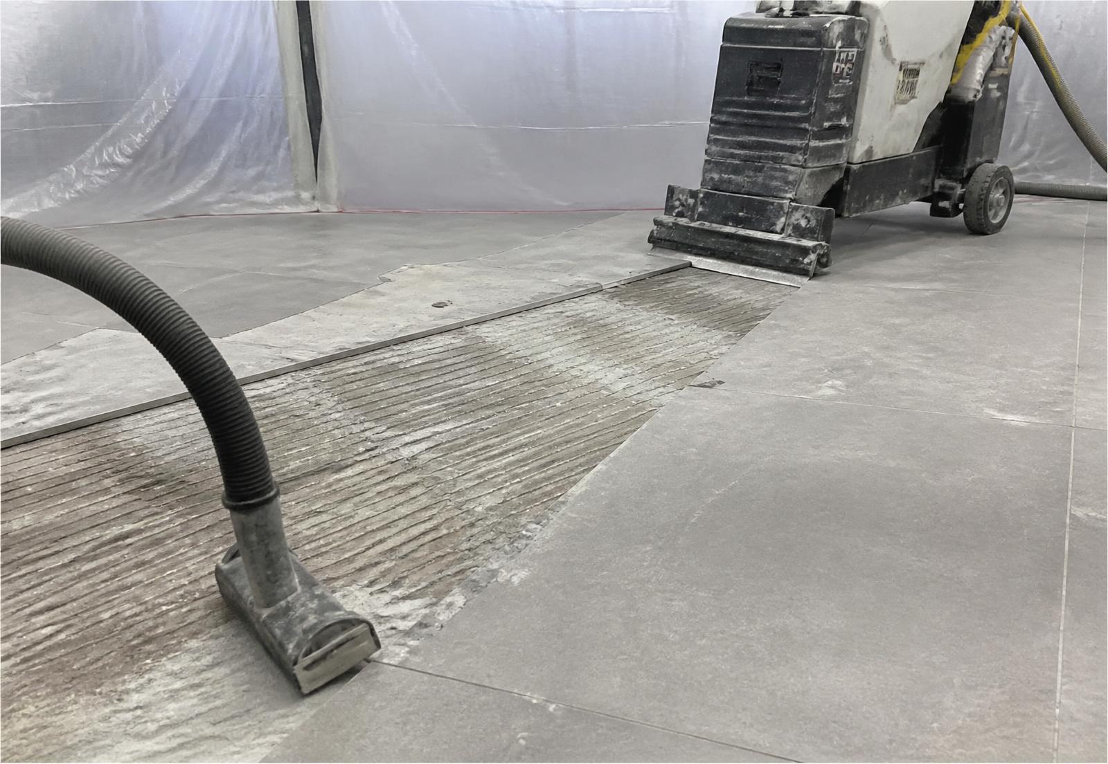 Tile removal in progress with dust extraction over a concrete slab